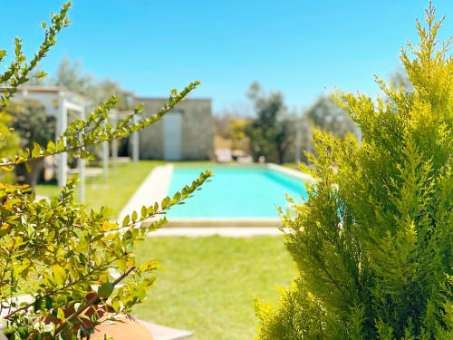 Masseria Vittoria's turquoise pool and manicured gardens with evergreens in Acaya, Vernole, Lecce