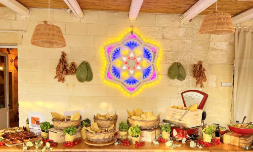 Masseria Vittoria dining display with neon mandala art, wicker baskets of fresh bread, and Italian produce at this Acaya B&B