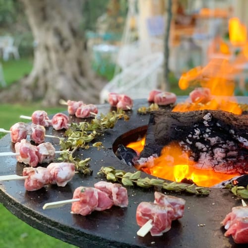 Grilled meat skewers with flowers over open flame at Masseria Vittoria, Acaya