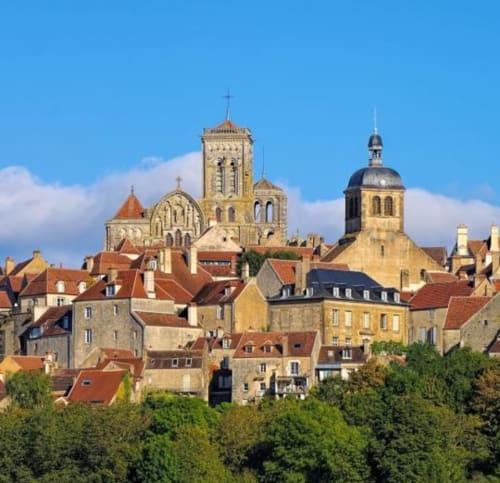 Medieval French village Pourrain with stone houses, red-tiled roofs, and historic churches under blue sky