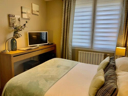 Chambre Be Hotel Le Touquet avec lit double, bureau en bois, TV écran plat et fenêtres avec vue sur la ville et volets