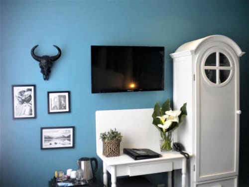Chambre moderne de l'hôtel Be Hotel Le Touquet avec murs bleus, bureau blanc, TV écran plat et vue sur la ville