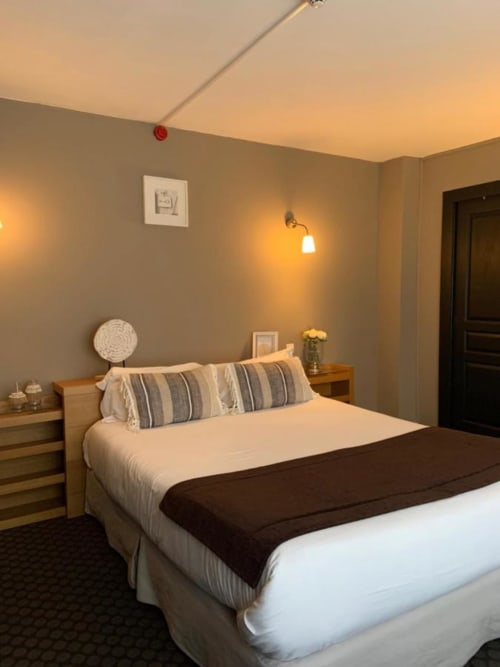 Chambre moderne de l'hôtel Be Hotel Le Touquet avec lit queen, oreillers rayés, tables de nuit en bois et éclairage ambiant chaleureux