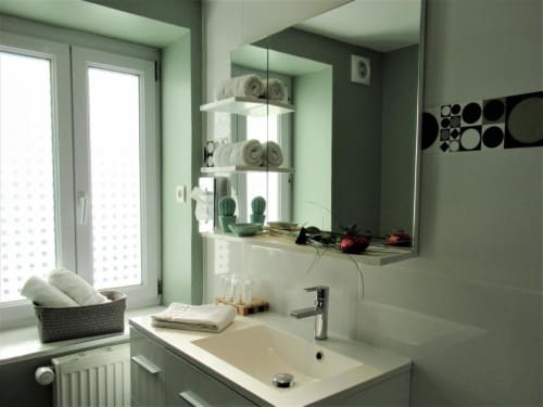 Salle de bain moderne au Be Hotel Le Touquet avec lavabo, miroir, rangements et vue sur la ville