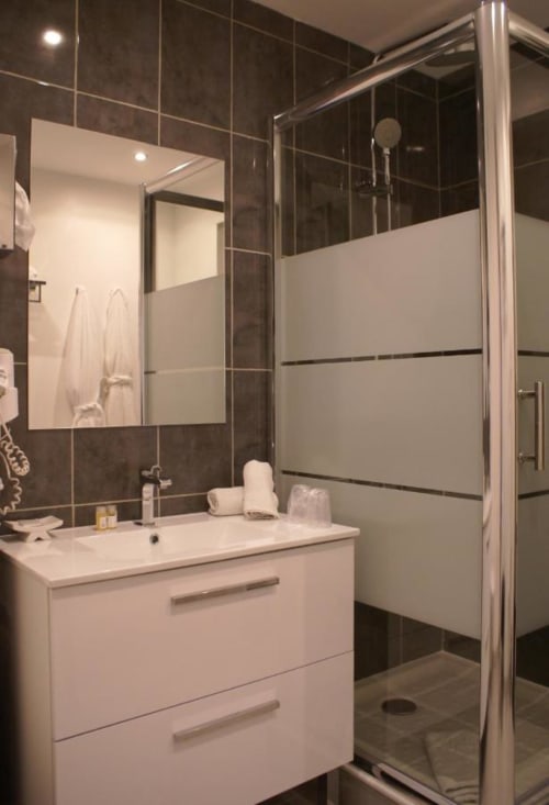 Salle de bain moderne de Be Hotel Le Touquet avec vasque blanche, murs carrelés foncés et douche à l'italienne