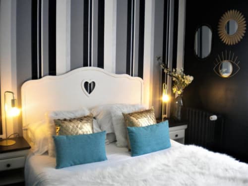 Chambre d'hôtel contemporaine au Be Hotel Le Touquet avec tête de lit blanche, coussins bleus, rideaux rayés et éclairage ambiant
