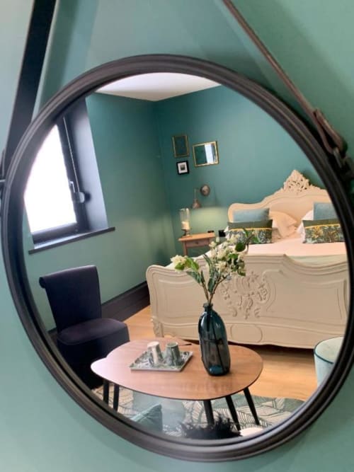 Chambre élégante du Be Hotel Le Touquet avec murs menthe, lit orné, miroir rond, table en bois et fleurs