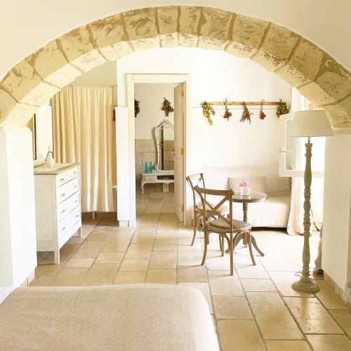 Suite Masseria Vittoria à Acaya avec plafonds en pierre voûtés, mobilier blanc et carrelage rustique