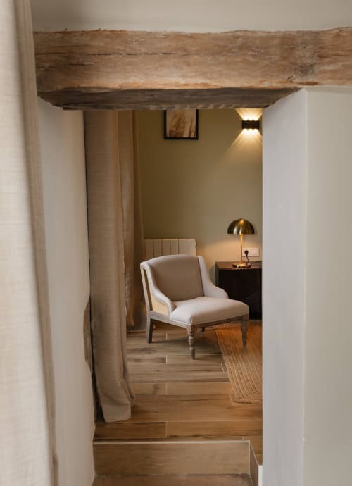 Rustieke houten deurkozijn naar de Saint Pierre kamer in Moulin Renaudiots, Autun, met beige fauteuil en warm licht
