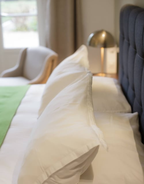 Elegant opgemaakt bed met witte kussens en bronzen lamp in de Saint Pierre kamer van hotel Moulin Renaudiots, Autun