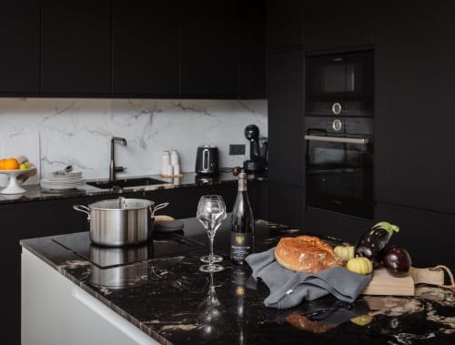 Moderne zwarte keuken in Maison Lùisa, Moulin Renaudiots, Autun met marmeren werkbladen, wijn, brood en verse groenten