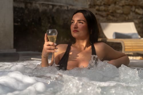 Femme détente dans un bain à remous avec champagne au spa-hôtel Le Pavillon M à Grignan
