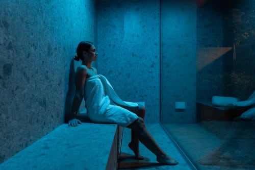 Clients détendus dans l'espace spa aux lumières bleues apaisantes du boutique-hôtel Le Pavillon M à Grignan, France