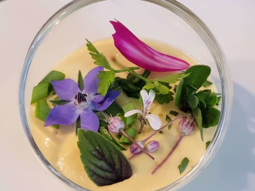Bol de soupe veloutée garni de fleurs comestibles éclatantes et herbes fraîches aux Clos des Moulins, Poitiers