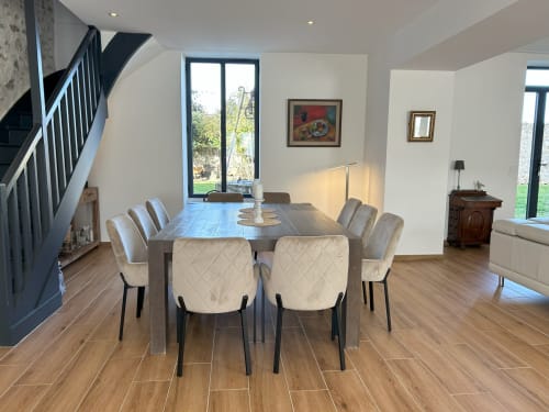 Modern dining room at La Ferme du Châtaignier with cream chairs, wooden table, and garden views near Paris