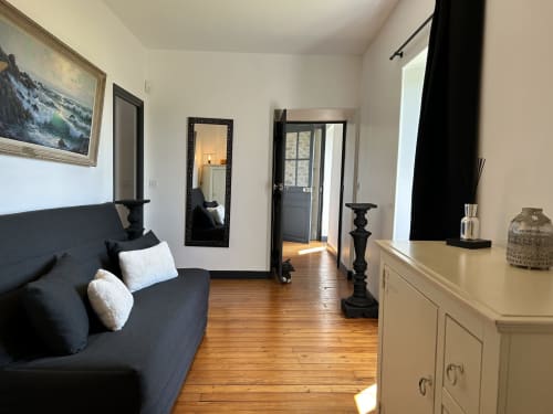 Suite élégante au gîte La Ferme du Châtaignier à Boissy-le-Sec avec parquet, canapé sombre et décoration classique