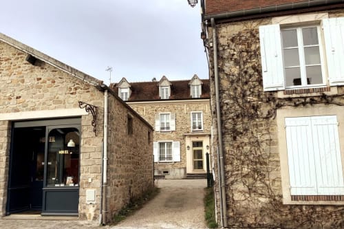 Entrée de cour en pierre de La Barbizonaise, gîte de Barbizon, aux murs couverts de lierre