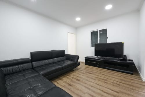 Sala de estar moderna com sofá de couro preto e TV de tela plana na villa Casa do Sol, Funchal