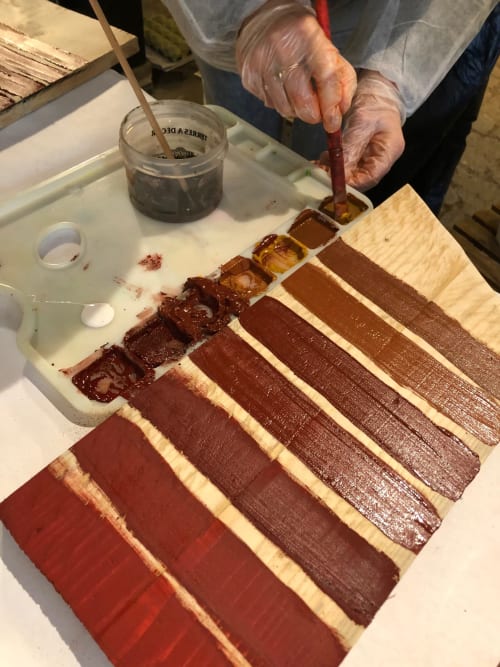 Fabric dyeing demonstration at Domaine de l'Ocrerie, showing progression of natural dyes from red to brown on wooden samples