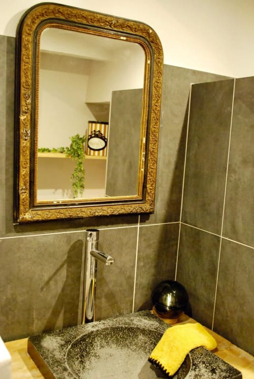 Élégante vasque en pierre et miroir doré ornementé dans la salle de bains de La vie de château B&B à Grignan