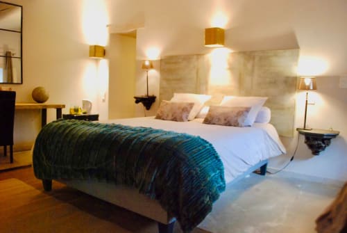 Chambre élégante à La vie de château B&B à Grignan avec plaid bleu-vert, literie blanche, luminaires dorés et vue sur les montagnes