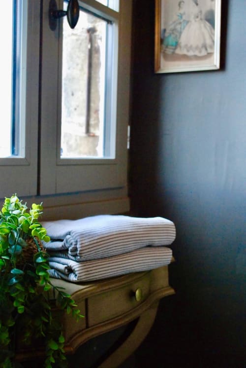 Serviettes rayées pliées sur un coffre en bois dans la chambre de Grignan avec vue montagne et fenêtres décorées