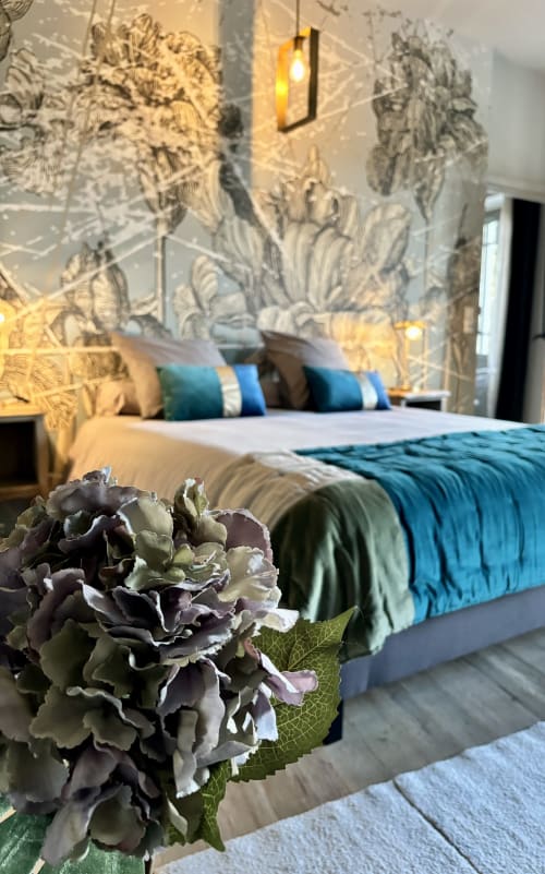 Chambre élégante à La vie de château à Grignan avec hortensia violet, décor mural raffiné, coussins bleus et éclairage chaleureux