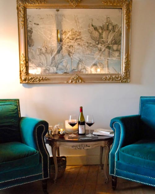 Élégant salon avec fauteuils en velours turquoise, verres de vin et art botanique encadré or à La vie de château, Grignan