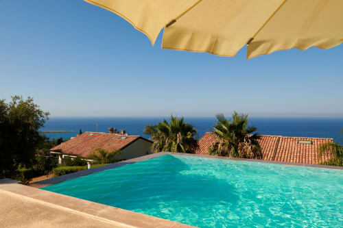 Luxury pool with turquoise water overlooking Mediterranean Sea, CefalHome property with palm trees and terracotta roofs