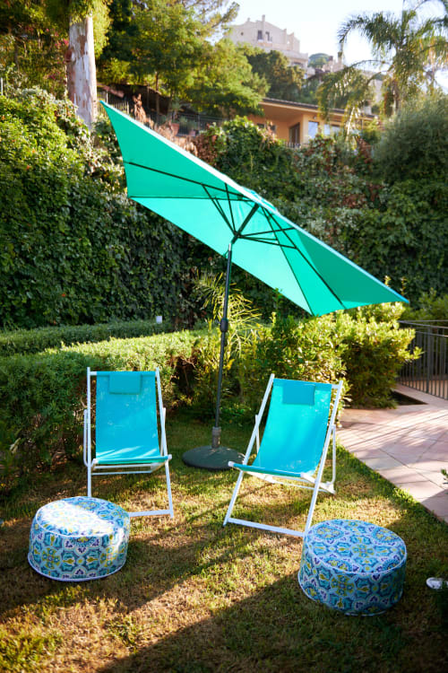 Lettini turchesi e ombrellone nel giardino rigoglioso dell'hotel CefalHome Roma