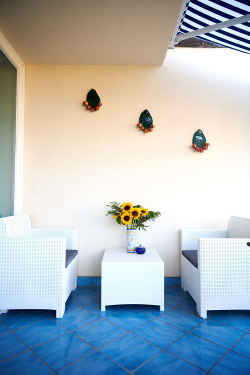 CefalHome Roma terrace seating area with white wicker chairs, sunflowers, blue tiles, and decorative wall art