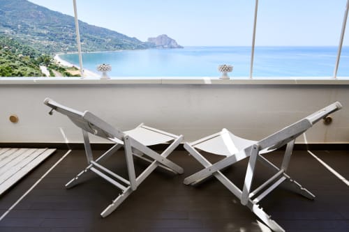 Two white lounge chairs on terrace overlooking turquoise Mediterranean sea and coastal mountains at CefalHome, Roma