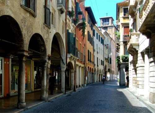 Storica strada in ciottoli a Treviso con portici ad arco, edifici colorati e negozi vicino all'Apartment GioviGemini