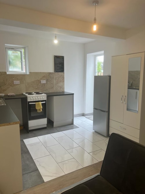 Modern kitchen in Starlet Property Garden Flat, London, with black and white cabinetry, stainless steel appliances, and tiled