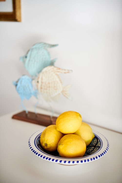 Fresh lemons in decorative blue and white bowl at CefalHome Roma, with coastal-inspired fish artwork