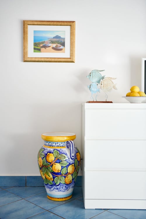 Mediterranean-inspired CefalHome Rome decor with ceramic lemon vessel, fish figurines, and coastal artwork on white cabinet