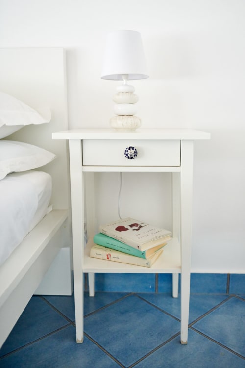 White nightstand with lamp and books beside bed at CefalHome Rome hotel