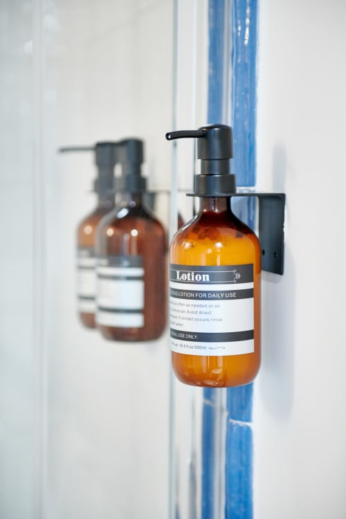 Amber lotion dispensers mounted on white wall at CefalHome hotel in Rome