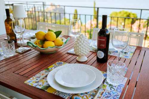 Elegant outdoor dining table at CefalHome Roma with wine, lemons, and place settings overlooking the city
