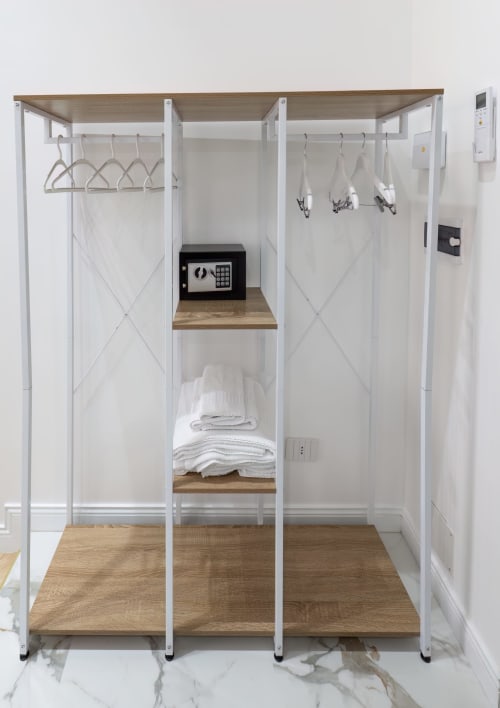 Moderna cabina armadio con telaio bianco, scaffali in legno, appendiabiti, cassaforte e asciugamani a Garibaldi 125 Napoli