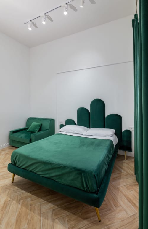 Letto e poltrona in velluto verde nella Superior Room moderna dell'hotel boutique Garibaldi 125 di Napoli, con vista sulla città