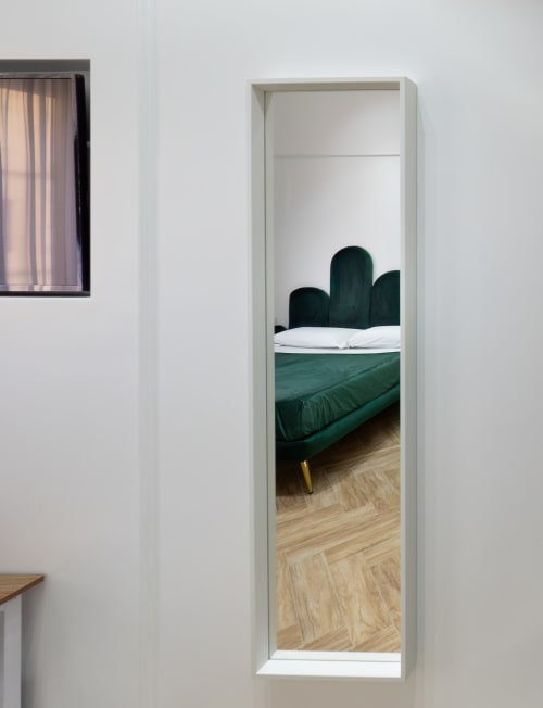 Specchio riflette letto in velluto verde con cuscini bianchi nella Superior Room dell'hotel Garibaldi 125, Napoli