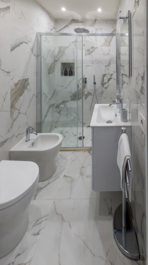 Elegante bagno in marmo della Suite Garibaldi 125, Napoli con doccia in vetro, sanitari bianchi e scaldasalviette