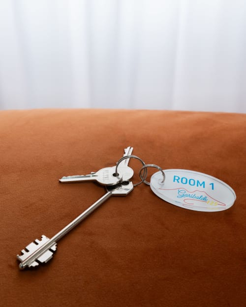 Hotel room key with white tag labeled 'ROOM 1' at Garibaldi 125 guesthouse in Naples on brown surface