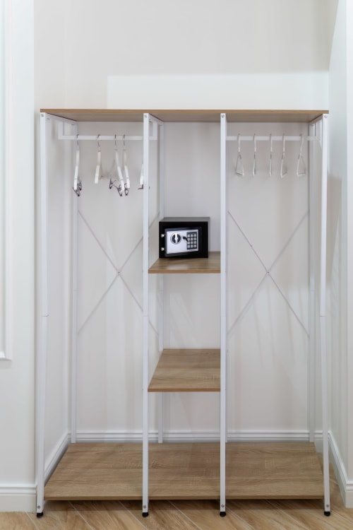 Modern walk-in closet with white storage units, wooden shelving, safe, and hangers at Garibaldi 125 Naples