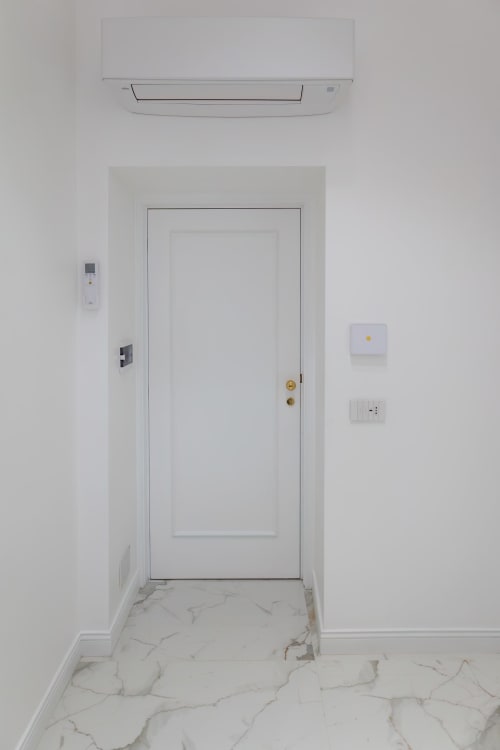 Entryway of Standard Room at Garibaldi 125 B&B in Naples with white door, marble floor, AC unit, and wall controls