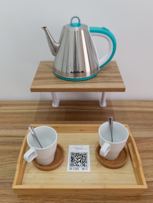 Tea service setup at Garibaldi 125 Naples with kettle, cups, saucers, and WiFi QR code on wooden tray