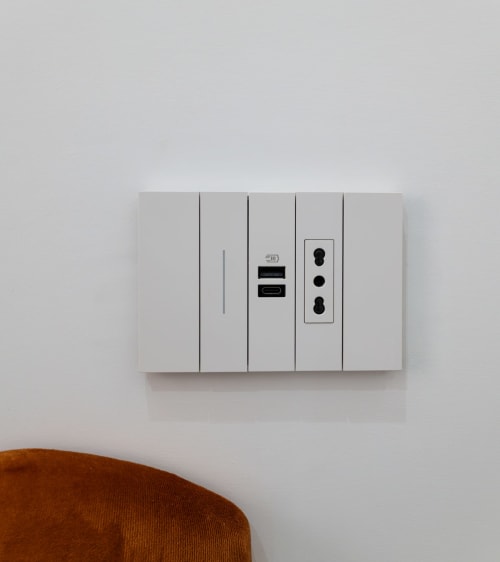 White wall outlet panel with USB ports and dual electrical sockets in Garibaldi 125 Naples hotel room