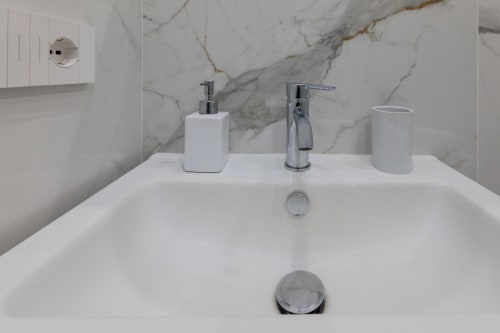 Modern bathroom sink with chrome faucet, soap dispenser, and marble backsplash at Garibaldi 125 bed and breakfast in Naples