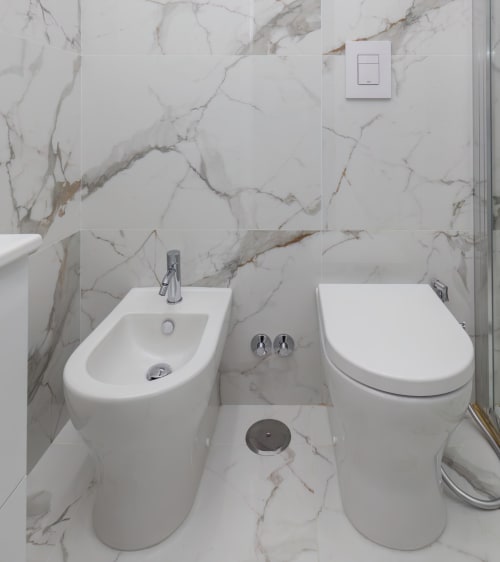 Modern bathroom at Garibaldi 125 Naples with marble walls, bidet, toilet, and chrome fixtures in Standard Room